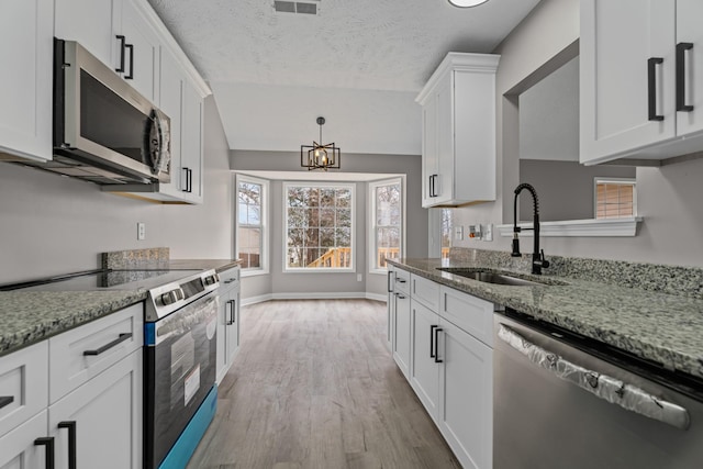 kitchen featuring white cabinetry, appliances with stainless steel finishes, sink, and light stone counters