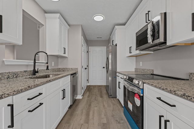 kitchen with white cabinetry, appliances with stainless steel finishes, light stone countertops, and sink