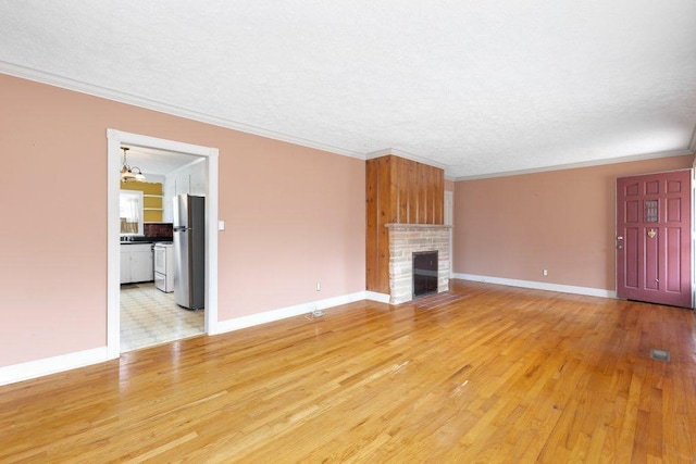 unfurnished living room featuring crown molding, a textured ceiling, a fireplace, and light hardwood / wood-style floors