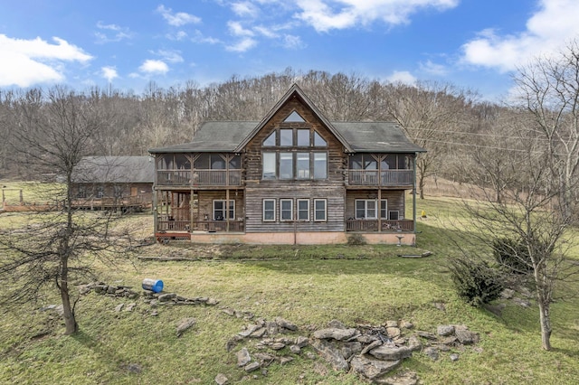 rear view of house with a deck, a sunroom, and a lawn