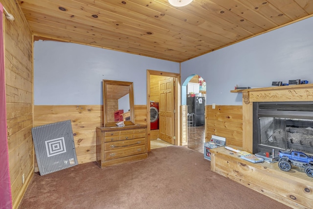 sitting room with carpet floors, wooden ceiling, and wood walls