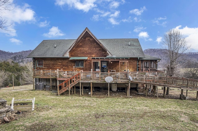 back of house with central AC, a deck with mountain view, and a lawn