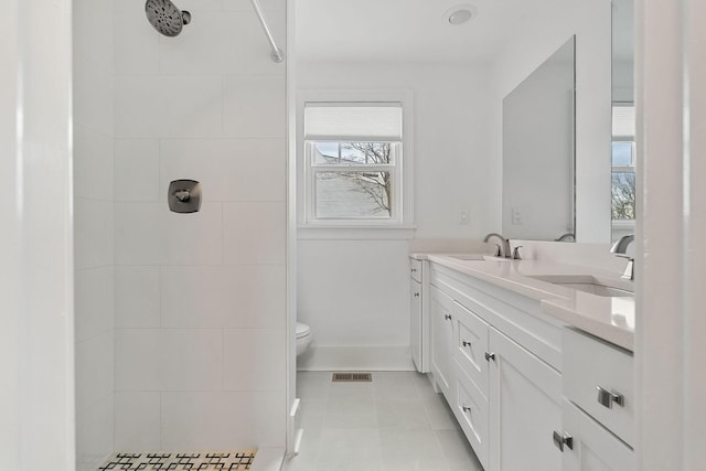 bathroom featuring vanity, tile patterned flooring, toilet, and tiled shower