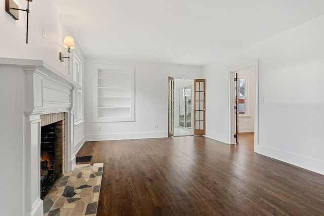 unfurnished living room with dark hardwood / wood-style floors, a fireplace, and built in features