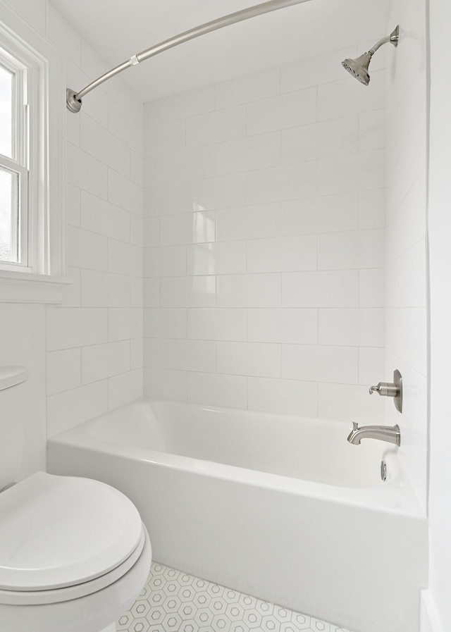 bathroom featuring tile patterned flooring, tiled shower / bath, and toilet