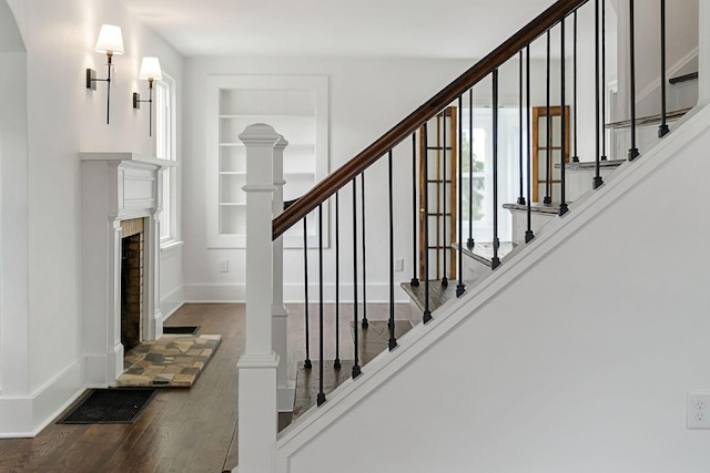 staircase with hardwood / wood-style floors and built in features