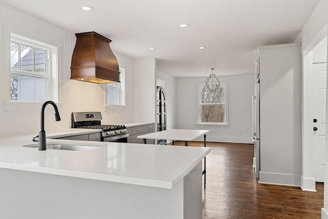 kitchen featuring premium range hood, sink, hanging light fixtures, kitchen peninsula, and stainless steel range with gas stovetop