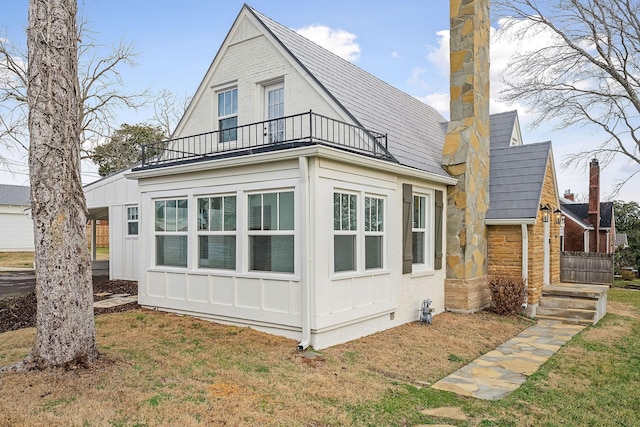 rear view of house featuring a balcony and a yard