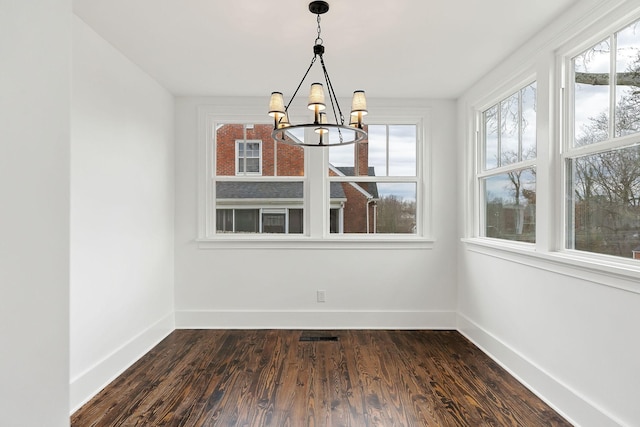 unfurnished dining area with dark hardwood / wood-style floors and an inviting chandelier