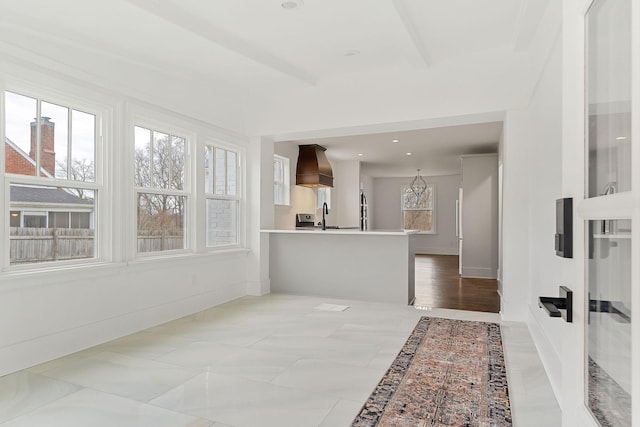 interior space with premium range hood, kitchen peninsula, and sink