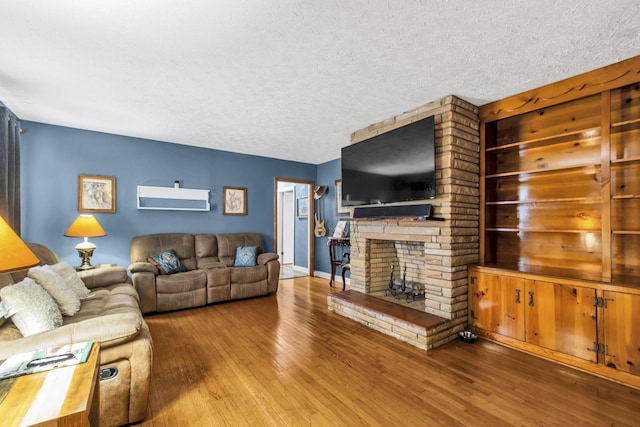 living room featuring wood-type flooring, a fireplace, and a textured ceiling