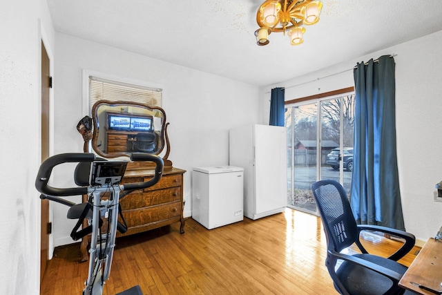 home office featuring an inviting chandelier and light hardwood / wood-style floors