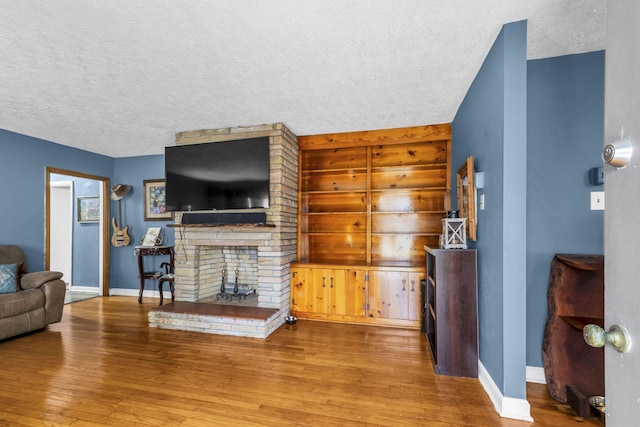 living room with a brick fireplace, hardwood / wood-style flooring, and a textured ceiling