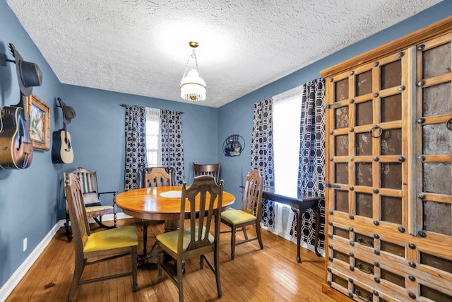 dining room featuring wood-type flooring and a textured ceiling