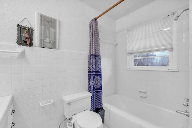 bathroom with tile walls, shower / tub combo, and toilet