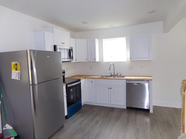 kitchen with butcher block counters, sink, stainless steel appliances, and white cabinets