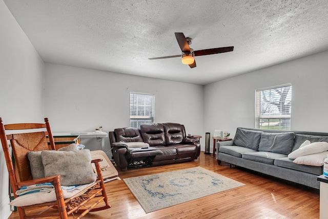 living room with a textured ceiling, ceiling fan, and light wood-type flooring