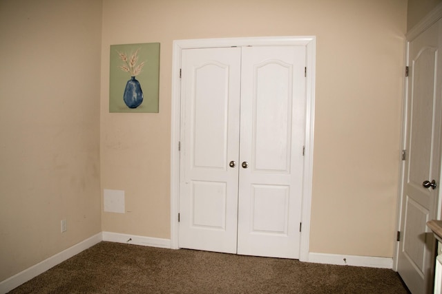 unfurnished bedroom with a closet and dark colored carpet