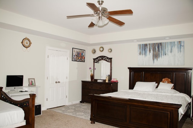 bedroom with light carpet, a raised ceiling, and ceiling fan