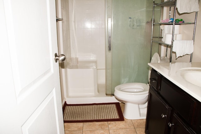 bathroom with tiled shower, vanity, toilet, and tile patterned flooring