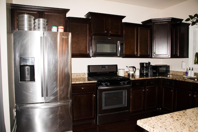 kitchen with light stone counters, stainless steel appliances, dark hardwood / wood-style floors, and dark brown cabinetry