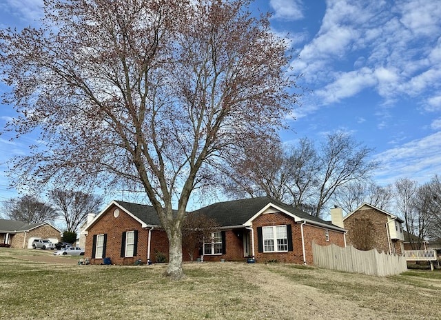 ranch-style house featuring a front lawn, fence, brick siding, and a chimney