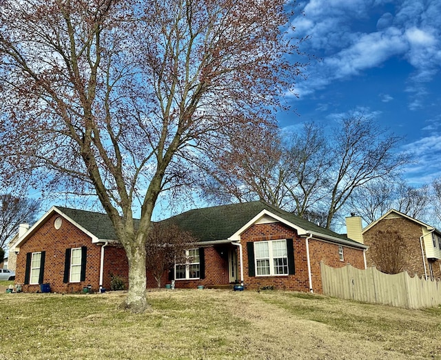 ranch-style home with a front lawn, fence, brick siding, and a chimney