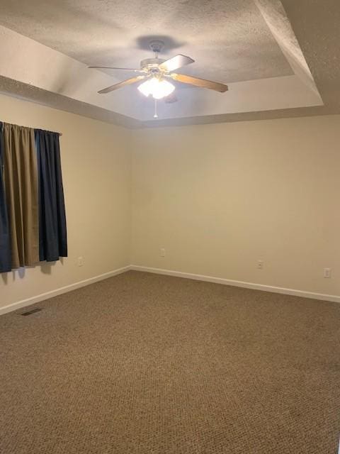 carpeted empty room featuring ceiling fan, a tray ceiling, and a textured ceiling