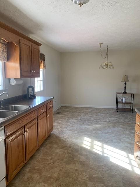 kitchen with an inviting chandelier, decorative light fixtures, dishwasher, sink, and a textured ceiling