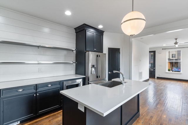 kitchen featuring appliances with stainless steel finishes, pendant lighting, sink, dark hardwood / wood-style flooring, and a kitchen island with sink