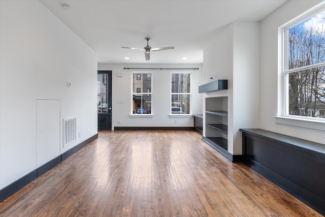 unfurnished living room featuring ceiling fan, a healthy amount of sunlight, and wood-type flooring