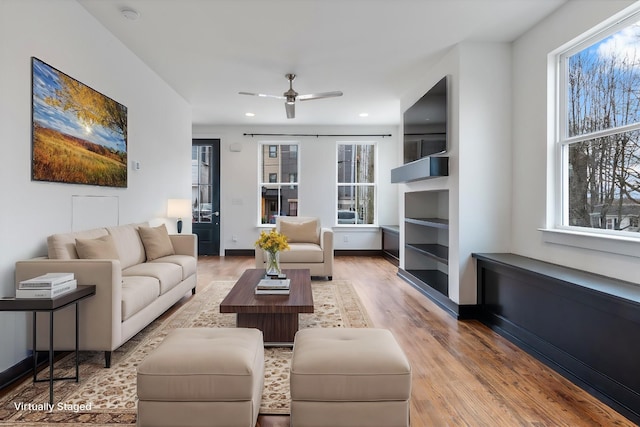 living room with ceiling fan, plenty of natural light, and light wood-type flooring