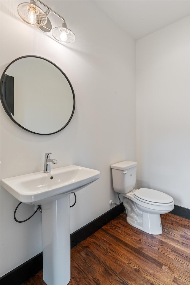 bathroom featuring wood-type flooring, toilet, and sink