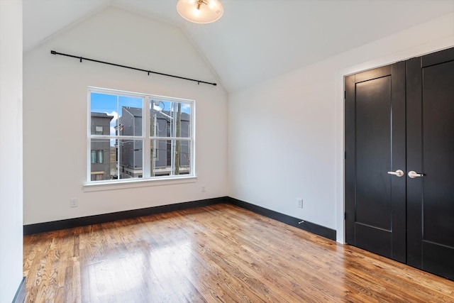 unfurnished bedroom featuring lofted ceiling and light wood-type flooring