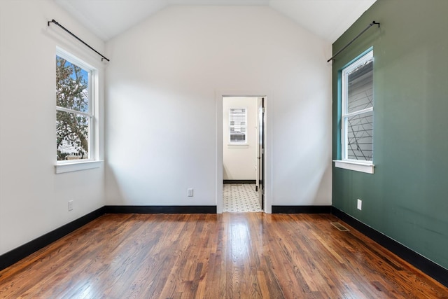 empty room with dark hardwood / wood-style flooring and vaulted ceiling