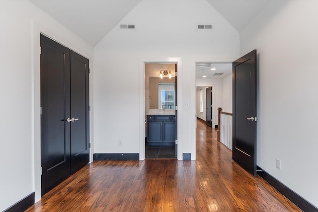 unfurnished bedroom with high vaulted ceiling, connected bathroom, dark hardwood / wood-style flooring, and sink