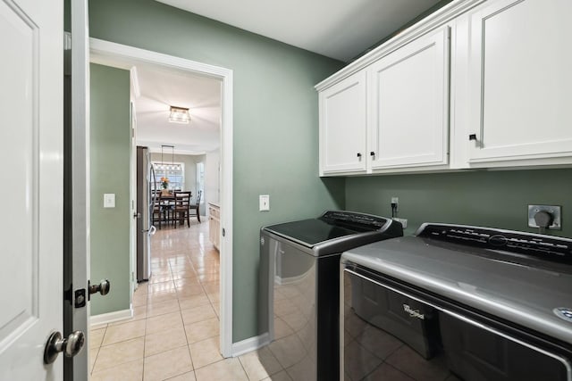 clothes washing area with cabinets, separate washer and dryer, and light tile patterned floors