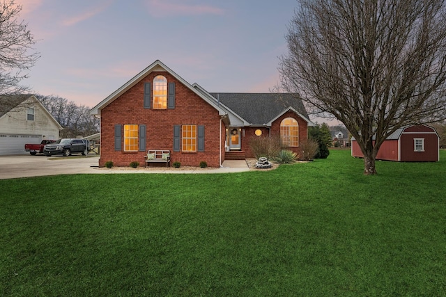 back house at dusk featuring a storage unit, a lawn, and a garage