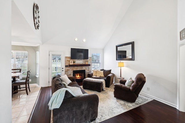 living room with high vaulted ceiling, a fireplace, and light hardwood / wood-style floors