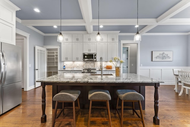 kitchen with coffered ceiling, a sink, decorative backsplash, appliances with stainless steel finishes, and beamed ceiling