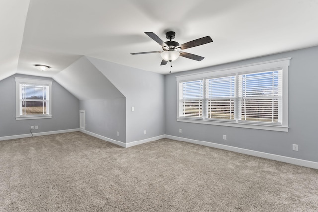 additional living space with carpet flooring, ceiling fan, baseboards, and vaulted ceiling