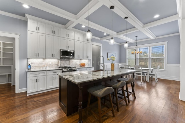 kitchen featuring a sink, stainless steel microwave, coffered ceiling, range, and dark wood-style flooring