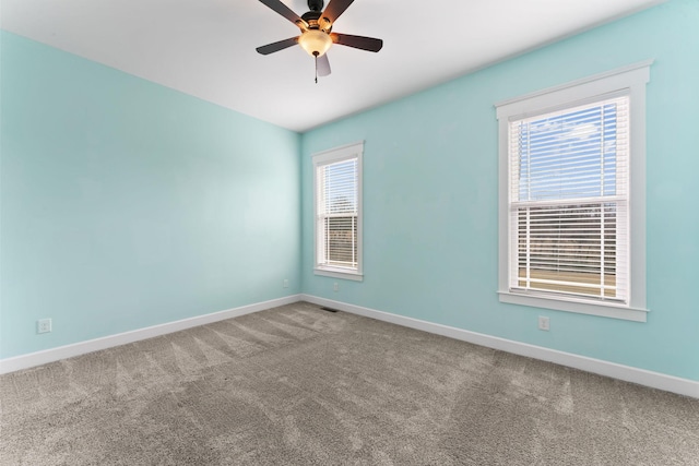 spare room with carpet flooring, baseboards, and a wealth of natural light