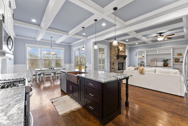 kitchen featuring beamed ceiling, a fireplace, a sink, appliances with stainless steel finishes, and a kitchen breakfast bar