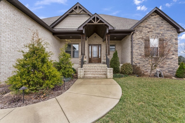 entrance to property featuring a yard, brick siding, and a shingled roof