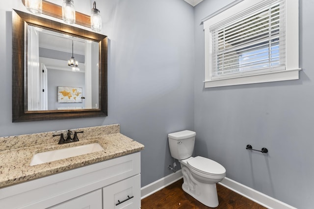 half bath featuring toilet, vanity, baseboards, and wood finished floors