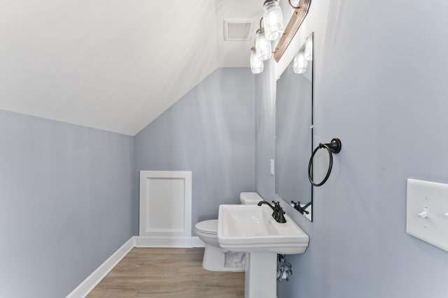half bathroom with wood finished floors, visible vents, baseboards, vaulted ceiling, and toilet