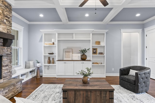 living room featuring coffered ceiling, ceiling fan, a stone fireplace, dark wood-type flooring, and beamed ceiling