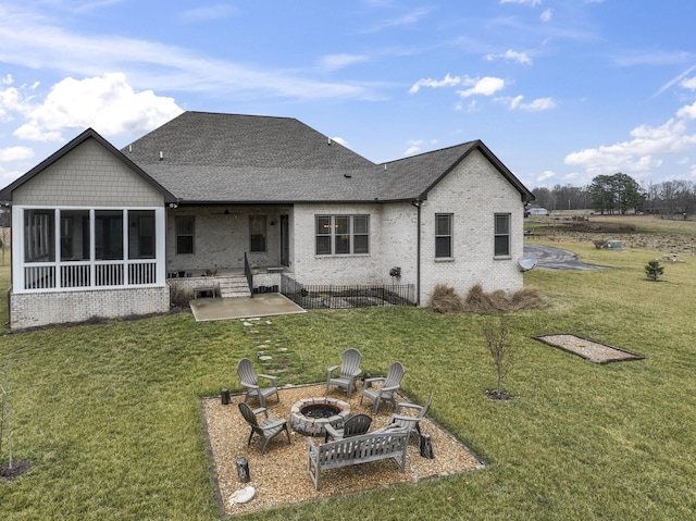 rear view of house featuring brick siding, a patio, a fire pit, and a lawn