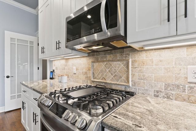kitchen with white cabinetry, backsplash, appliances with stainless steel finishes, and ornamental molding